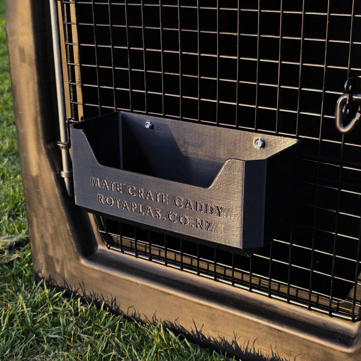 A black dog crate caddy hooked onto the door of a black Rotaplas Mate Crate made to store dog accessories